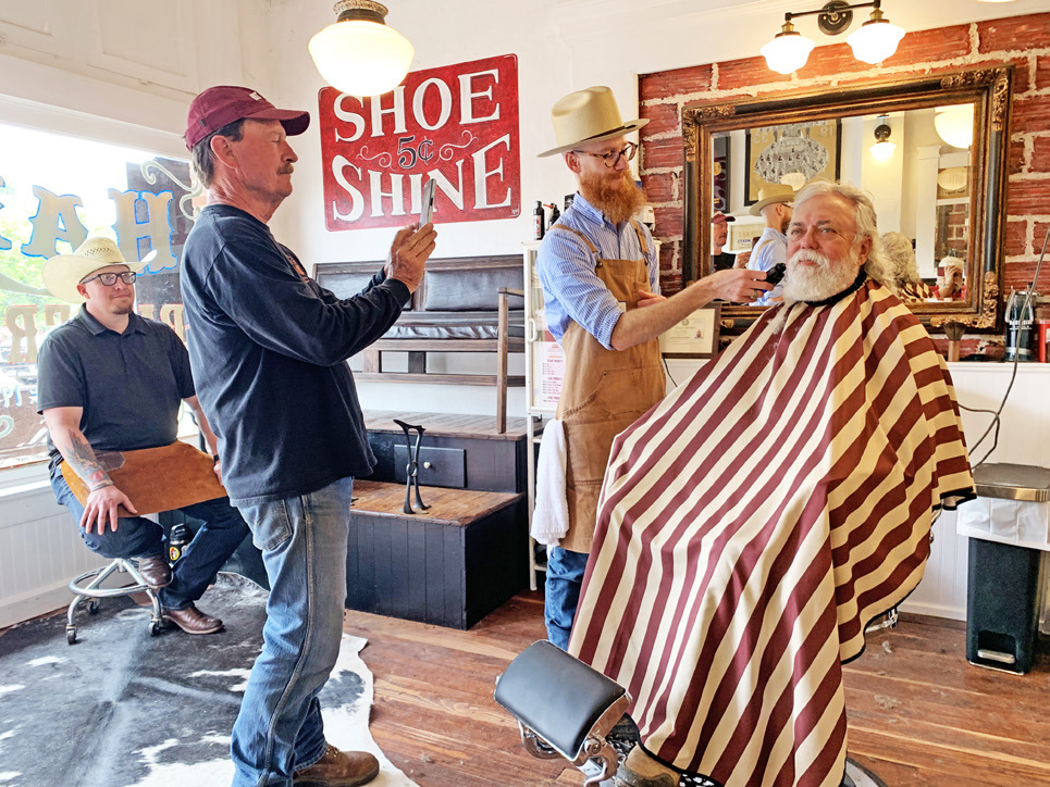 TURKEYBEARD Austen Covin trimsWylie Bomar’s beard Saturday at the historic Ham’s Barber Shop in Turkey, where Bob Wills once gave shaves and haircuts. Snapping a picture is owner Mike Goldsby; taking a break is the shoeshine boy, Josh Kreusel. Shaves, haircuts, shoeshines and tours of the refurbished building were free on Saturday, compliments of Goldsby. Reporterphotographer Hanaba Munn Welch is visible in the bottom right corner of the mirror. SEE SPOTLIGHT PHOTOS, PAGE 10 | HANABA MUNNWELCH
