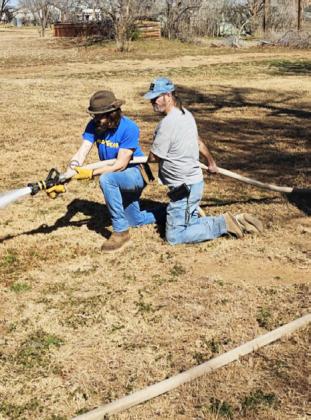 “KID” KELLICK AND CHARLIE MINICK man the fire hose to wash out a silted city culvert Thursday. | COURTESY PHOTO