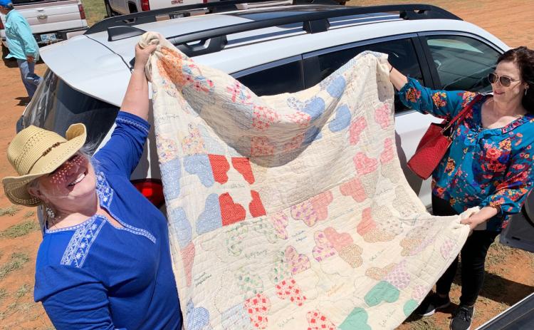 STITCHED WITH LOVE An old friendship quilt bears the names of some Turkey quilters. Sheila Smith and Barbara Brannon (in hat) display the quilt in the midday sun on Bob Wills Day in the Bob Wills Museum parking lot. Smith took the quilt to Turkey in hopes of finding it a home. | PHOTO BY HANABA MUNNWELCH